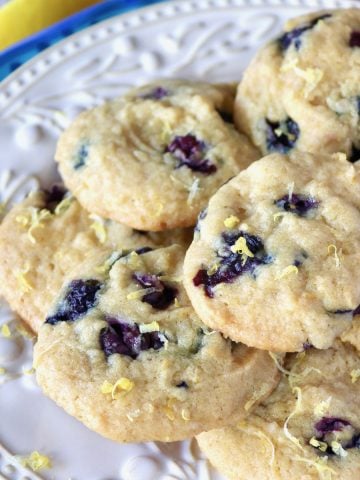 Cream-colored plate on top of a blue-rimmed plate with layered lemon blueberry cookies.